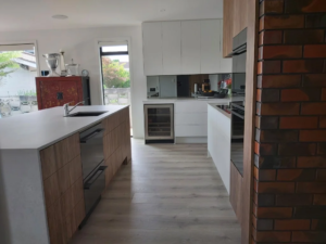 local Waikato cabinet makers featuring white and timber veneer cabinetry, an integrated under-bench wine fridge, and a custom island unit by Hamilton Kitchens